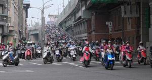 Eine große Anzahl von Motorrädern und -rollern fährt eine Brücke hinab.